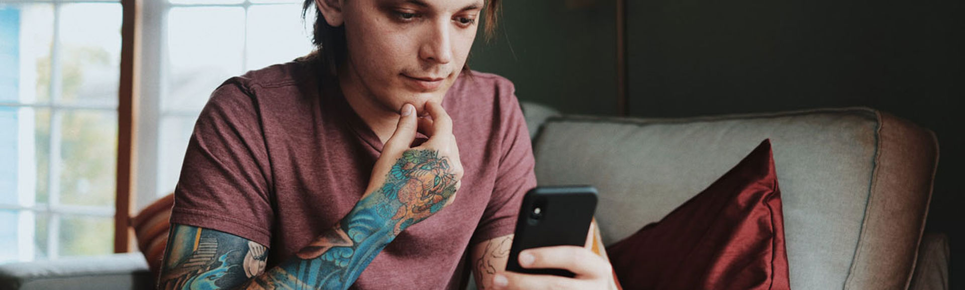Man with sleeve tattoo looking at a mobile phone