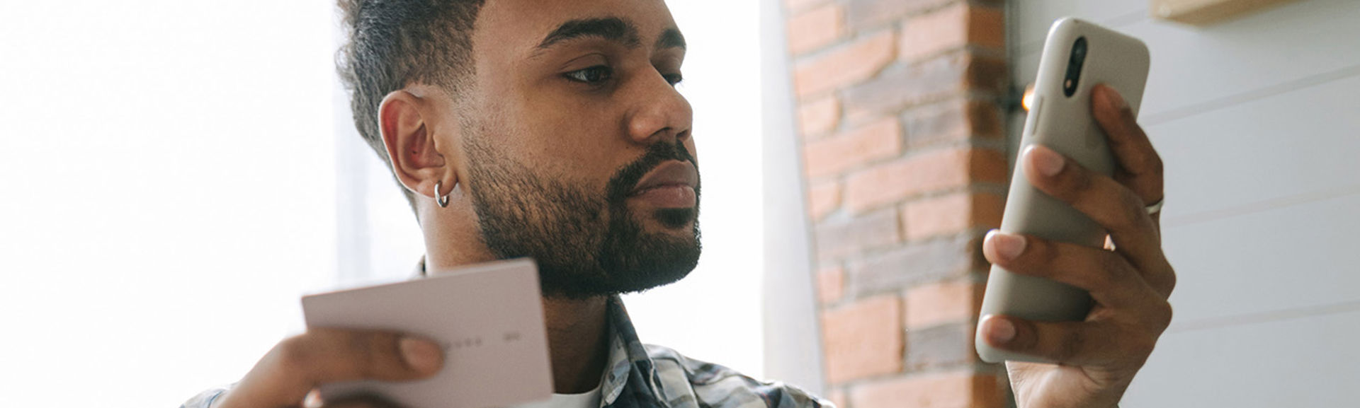 Young man looking at his phone while holding a credit card